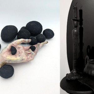 hand holding black rocks in front of a candlestick that is black